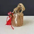 Detail view of the handmade woven mini straw basket with red ribbon and jute handle. - 10*10cm / Red Flower Basket