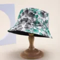 Close-up of reversible bucket hat with green leaf print on wooden stand - Green Grey Leaf Print