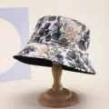 Detailed view of a reversible floral print bucket hat on a wooden display stand - Adult 55-58cm / Grey Yellow Leaf Print Style (4) / Grey Yellow Leaf Print