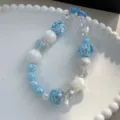 Hand-painted blue and white candy-style beaded phone charm with blue lobster clasp - Blue & White