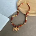 Detailopname van een Boheemse kralenketting met een gouden zebra-hanger - Goud Rood