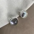 Vista macro de pendientes de resina transparente sobre fondo de tela texturizada - Pendientes de botón