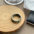 Makrodetail eines Retro-Harzrings mit Dalmatinerstein-Muster auf einem Holzständer - Gefleckter Stein Stil