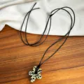 Close-up detail of a minimalist spotted flower pendant necklace with adjustable black cord - Dalmatian Jasper Flower