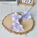 Close-up detail of three purple silk oil painting lilies on a rustic wooden slice base - Purple