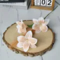Close-up of artificial oil painting lilies with soft apricot petals on a wooden base - Orange