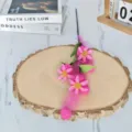 Primer plano de una rama de fruto de amapola de espuma rosa sobre una rodaja de madera rústica - Rosa rojo