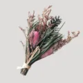 Vue détaillée du petit bouquet de fleurs séchées avec accents roses et feuillage vert. - Herbe verte et boules d'allium roses