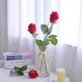 Detail of realistic moist-touch artificial red rose buds in a glass vase for home decor - Red