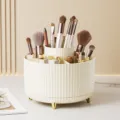 Cream rotating makeup brush organizer with ribbed texture and elegant gold feet. - Cream