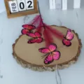 Nahaufnahme von realistischen rosa Schmetterlingsblumen auf einer rustikalen Holzscheibe - Fuchsia