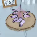 Künstliche Schmetterlingszweige auf einer natürlichen Holzscheibe für Wohndekoration - Rosa