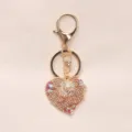 Close-up of heart-shaped keychain with pearls and crystals on beige background - Beige