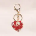 Close-up of heart-shaped keychain with red rhinestone rose and gold clasp - Red