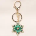 Elegante llavero de copo de nieve con cristal verde y aleación dorada para bolsos y más - Verde