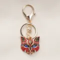 Retro fox mask keychain crafted in gold-toned alloy with vibrant enamel and rhinestones - Red
