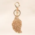 Vintage pauw sleutelhanger met strass steentjes in een elegante champagne goudkleur. - Champagne