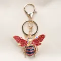 Vintage roter Bienen-Schlüsselanhänger mit funkelnden Strasssteinen und Blumendetails. - Roter Strass-Stil / Rote Biene