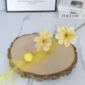 Primo piano di fiori di cosmos artificiali gialli su fetta di legno per arredamento. - Giallo