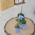 Detail einer blauen künstlichen Kosmosblume mit 4 Köpfen auf einer rustikalen Holzscheibe - 4-Kopf Cosmos / Blau
