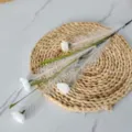 Gros plan de roseau artificiel avec petites fleurs blanches sur un tapis de paille - Blanc