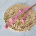 Detailed view of pink artificial reed branch with flowers on a woven straw mat - Pink