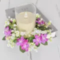 Close-up van een kunstmatige bloemenkaarsring met roze en witte wilde bloemen - Donkerpaars