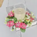 Detailweergave van een roze en witte kunstmatige bloemenkrans rond een kandelaar op een tafel - Dieproze