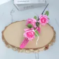 Nahaufnahme von drei rosa Schaumrosen auf einer Holzscheibe für Deko - Fuchsia