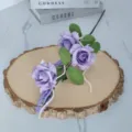 Detailansicht von drei lila Schaumrosen mit grünen Blättern und dekorativen Perlen - Lila