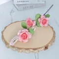 Detailansicht von künstlichen rosa Schaumrosen mit drei Köpfen auf einer rustikalen Holzscheibe - Rosa