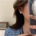 Eleganti orecchini a lobo con grandi perle indossati da una modella per un look chic - Orecchini a Bottone Perla di Cotone (R0106) / 12mm