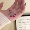 Dettaglio di un'elegante collana di zirconi a goccia con pietre rosa tenuta in mano - Anello Retrattile a Goccia d'Acqua (R0703) / Rosso rosa