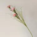 Vue détaillée de fleurs d'œillets artificiels roses avec un feuillage vert réaliste. - Rose