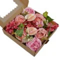 Détail d'un coffret cadeau de roses et pivoines artificielles dans une boîte en papier kraft - Rose rouge