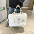 Detailed view of the white quilted travel duffel bag with bottom compartment and dual handles. - White