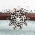 Detailopname van een elegante vintage sneeuwvlokspeld met witte parels en gouden afwerking - Kunstparel Stijl / Vintage Koper (l3)