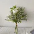 Gedetailleerde close-up van een kunstmatig wit ranonkel- en eucalyptus handboeket - Wit