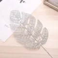 Detailed close-up of silver glitter monstera leaf decoration for Christmas tree and floral arrangement. - Silver