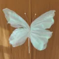Close-up detail of iridescent gauze butterfly with pearl accents for wedding decor - Colorful White