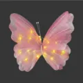 Detailansicht eines rosa leuchtenden Gazeschmetterlings mit warmen LED-Lichtern und Perlen - Rosa