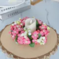 Vue détaillée de l'anneau de bougie floral rose avec bougie blanche sur bois, déco. - Rose foncé
