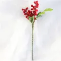 Gros plan d'une branche de baies rouges artificielles, détail parfait pour décoration de Noël. - Rouge