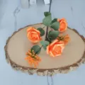 Detalle de rosas artificiales naranjas con bayas de Milán sobre una base de madera - Naranja