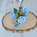 Primer plano de rosas artificiales azul claro y bayas de milán sobre rodaja de madera - Azul
