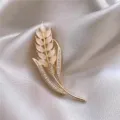 Détail macro d'une élégante broche épi de blé dorée avec des pierres opalines brillantes - Petite Broche Blé(2270) / Or