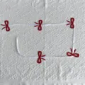 Detailed view of a festive red bow garland banner on textured white fabric background - Red Bow