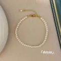 Nahaufnahme eines minimalistischen 4mm weißen Perlenarmbands mit goldenem Verschluss - Armband / 4mm / Weiß