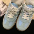 Detailed view of elegant white pearl bow shoe charms on light blue sneakers. - Bow Style (R2595) / One Pair