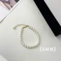 Macro view of 6mm white pearls and gold-plated extender chain on a minimalist bracelet. - Bracelet (A76)